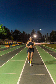 Female runner check smartwatch on track at night