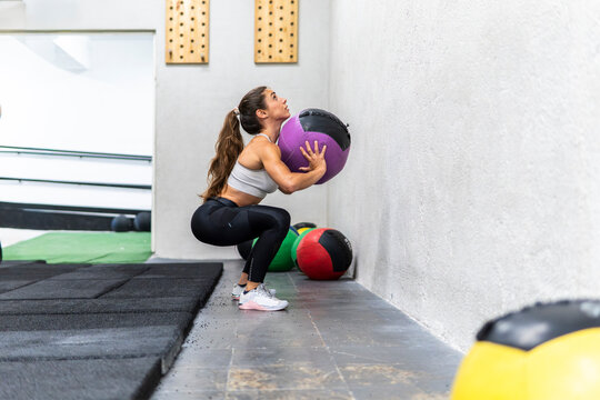 Woman perform wall ball squat exercise in gym