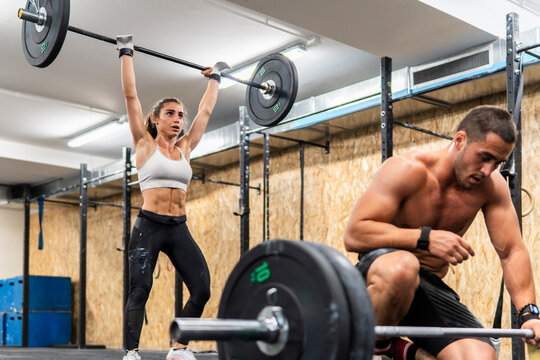 Couple training with barbells during a strength workout at a gym