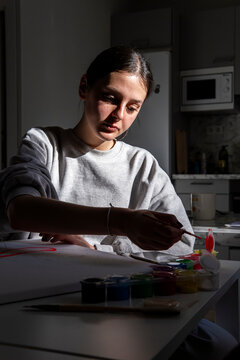 Woman paint artwork at home in natural window light