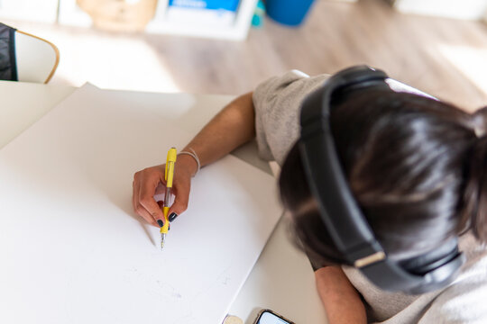 Woman draw at home while wearing headphones