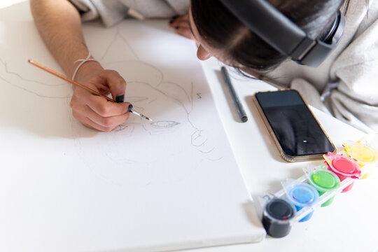 Woman paint artwork at home while listening to music
