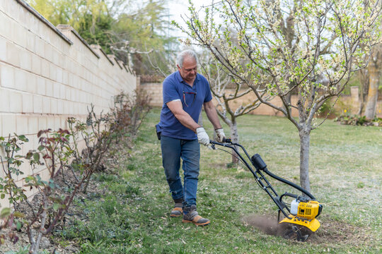Man use motorized tiller to prepare backyard garden soil
