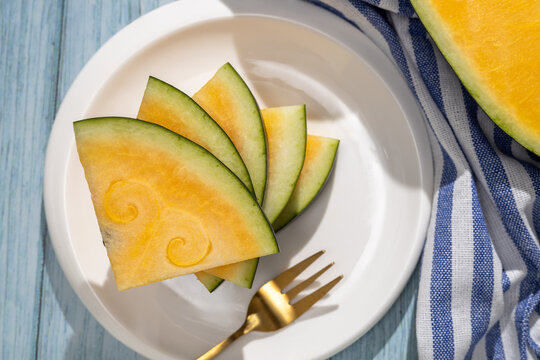 Yellow watermelon slices on plate with fork and cloth