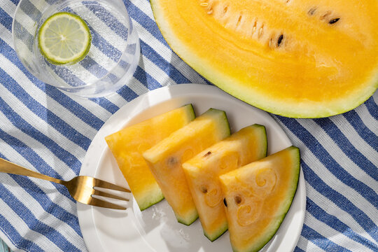 Yellow watermelon slices with lime water on striped cloth