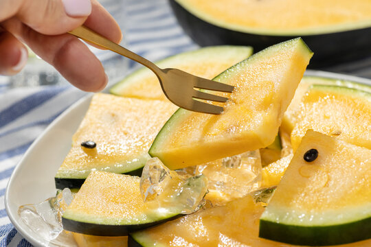 Yellow watermelon slice with fork on ice for summer dessert
