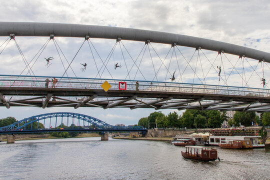 Balancing acrobatic sculptures suspended above the Vistula River on Father Bernatek Footbridge. Created by Polish sculptor Jerzy Kędziora. Suspended across the bridge. Krakow, Poland, June 9, 2026. 