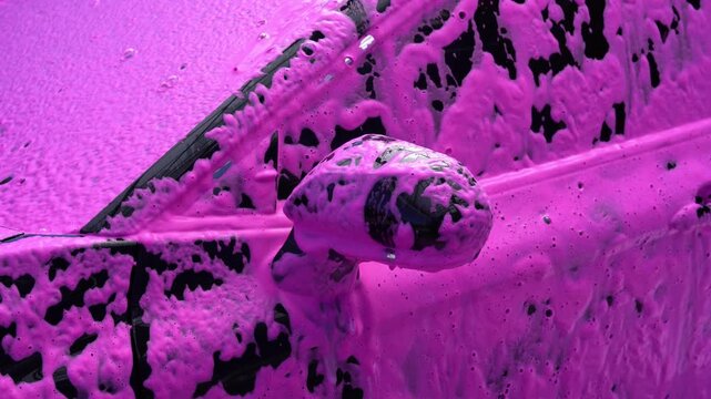 Car wash with pink foam covering the vehicle surface