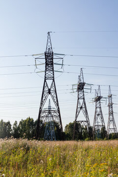 Power transmission tower line across rural meadow landscape