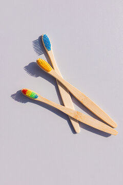 Bamboo toothbrushes with colorful bristles on a gray background