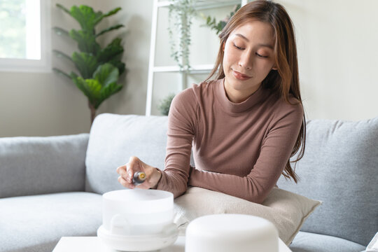 Women drop essential oil into the humidifier to make aromatherapy refreshments atmosphere house for relaxation.