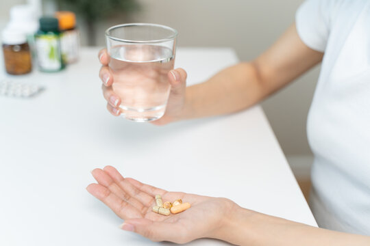 close up person pouring multivitamin capsules to her hands