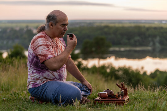 Man practicing tea ritual outdoors at sunset