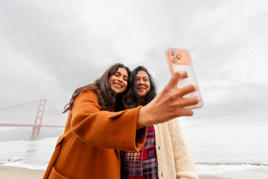 mom and daughter take selfie with landmark using cellphone together