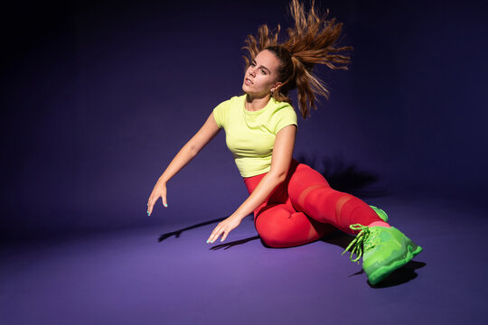Woman dancer in vibrant fitness outfit on purple background