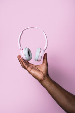 Black man hand holding pink wireless headphones
