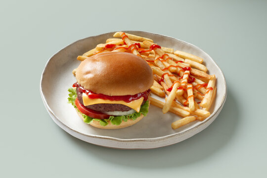 Cheeseburger with ketchup and french fries on ceramic plate