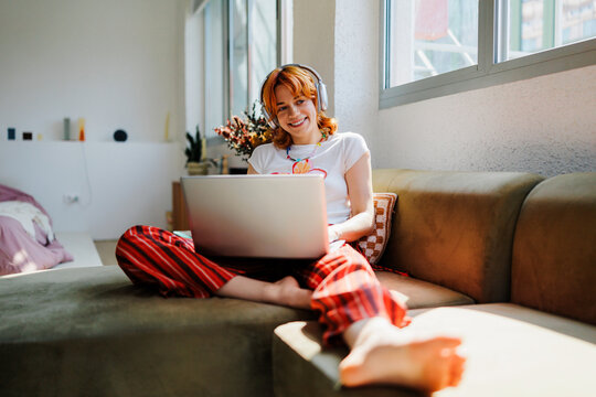 Woman enjoying home entertainment streaming with laptop headphones