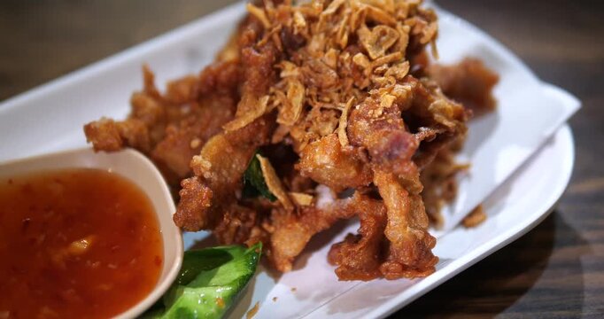 Close up of crispy deep fried pork belly topped with fried garlic and dipping sauce