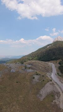 Aerial Drone Shot of Winding Road in Visočica Mountain Range towards Distant Ranges