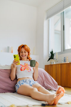 Woman enjoying morning coffee and phone at home