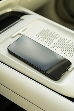 Smartphone on wireless charging pad in electric car console
