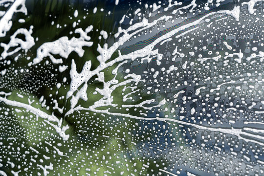 Soap foam and water droplets on car window during wash