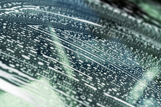Soap foam on car windshield during outdoor car wash