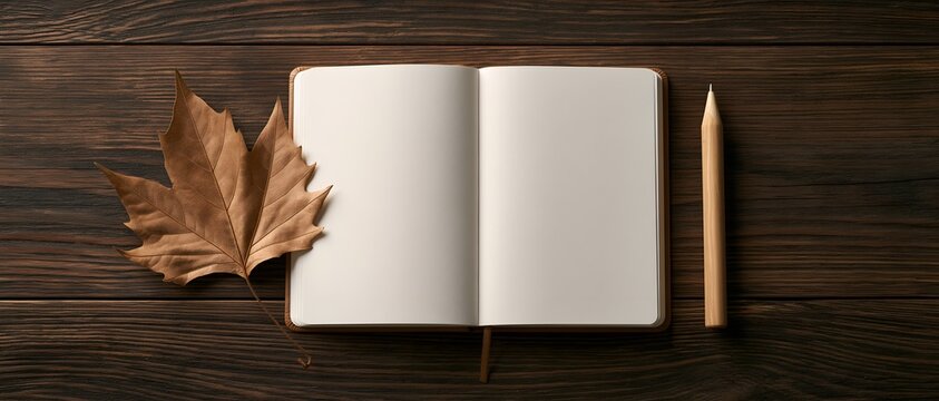 Empty journal with pencil and maple leaf on dark wood background