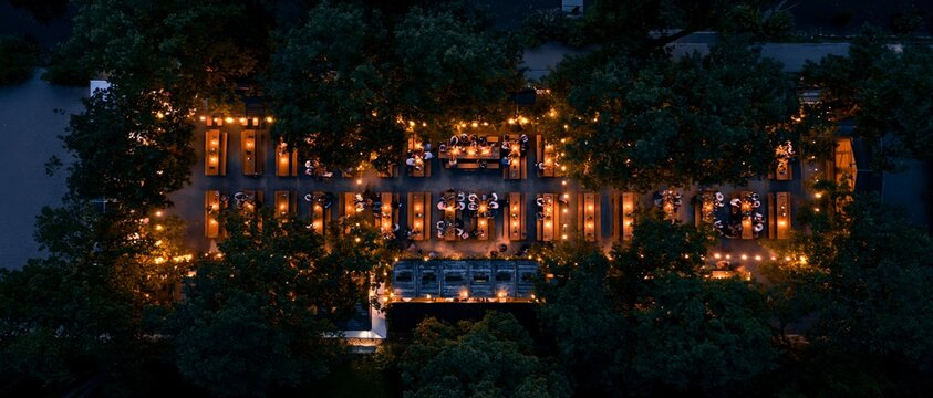 Night aerial shot captures a stately building glowing among towering trees