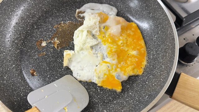Close up view of a griddle with cooking food items, fluffy white and yellow textures visible, suggesting breakfast preparation or cooking process, warm kitchen setting atmosphere