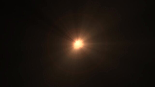 Glowing golden lens flare with radiant light rays and soft circular halo on dark background, suitable for cinematic transitions, overlays and visual effects transparent background with alpha channel