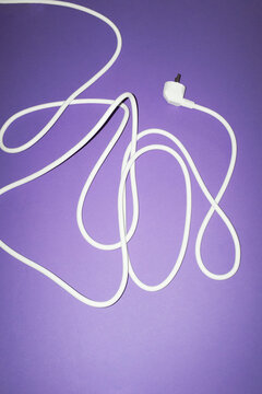 White electrical cord with plug on purple background