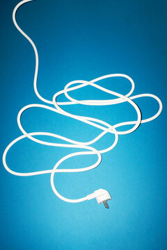 White electrical cord with plug on blue background