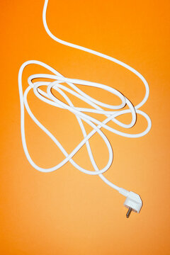 White electrical cord with plug on orange background