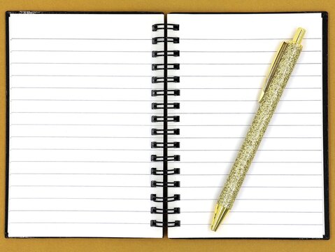 Gold pen resting on an open spiral-bound notebook. Space for text.