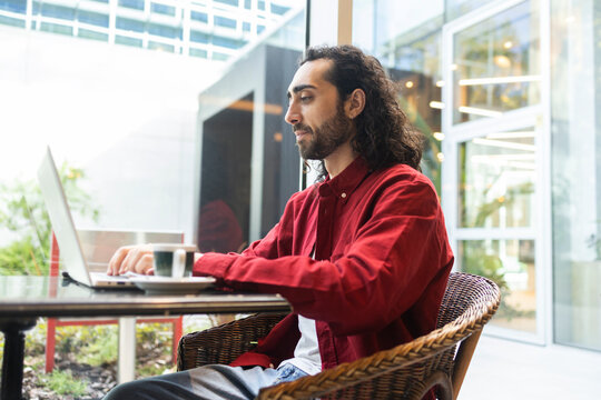 Man working on laptop in modern cafe terrace