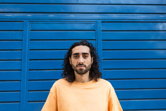 Man in yellow shirt against blue city wall