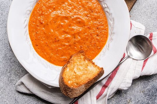 Tomato veloute soup with toasted bread and spoon