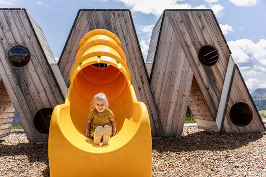 Child on yellow playground slide in the Dolomites, Italy