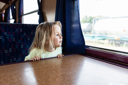 Young girl look through train window during journey