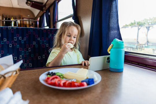Girl eat snack during train journey with smartphone