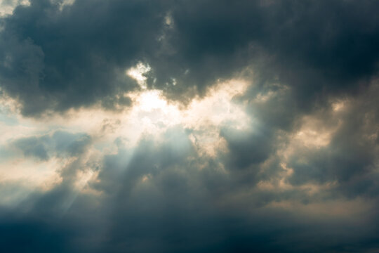 Dramatic sun rays piercing through dark, heavy storm clouds in the sky over Xizhi, New Taipei City, Taiwan.