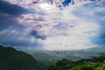 Fototapeta premium Panoramic view of Taipei city from Datianjian Mountain in New Taipei City, Taiwan, featuring dramatic clouds and sun rays.