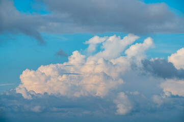 Fototapeta premium Fluffy white clouds and dark storm clouds floating across a vibrant blue sky, captured from Mount Shizitou in New Taipei City, Taiwan.