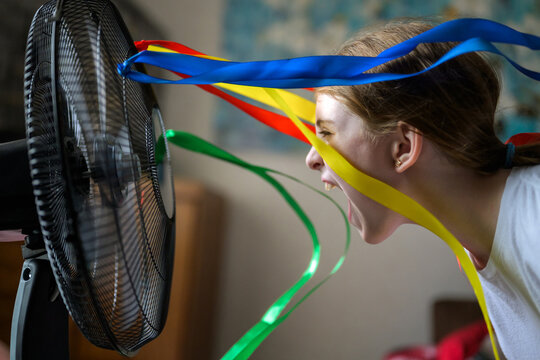 Joyful child cool down with fan and flying ribbons