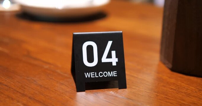 Close up of table number 04 welcome sign on wooden table in restaurant