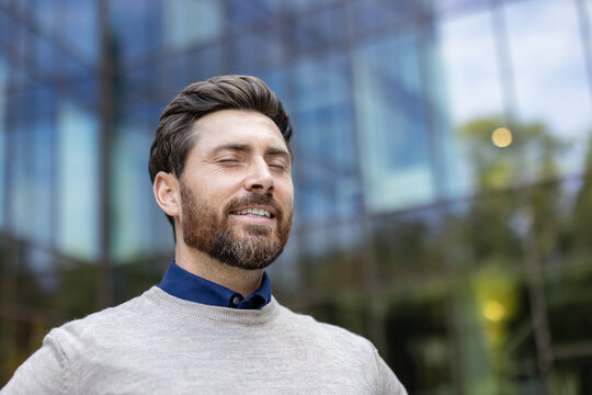 Close-up photo of a young man standing contentedly on the street with his eyes closed