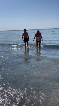 Ba&ntilde;arse en mar matrimonio mayor ba&ntilde;&aacute;ndose en orilla de playa viejos en ba&ntilde;ador mayores con sombrero entrando al agua a ba&ntilde;arse al mar con ba&ntilde;ador y viejos con sombrero tercera edad paz y tranquilidad 