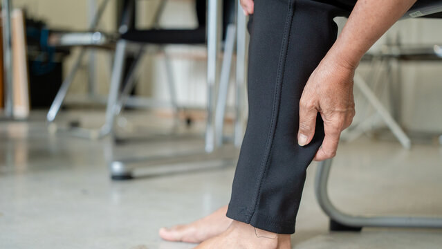 Close up of elderly woman hand massages and relieves pain in knee, related to osteoarthritis, tendon and muscle inflammation. Senior patients with symptoms Knee inflammation, arthritis, osteoporosis 